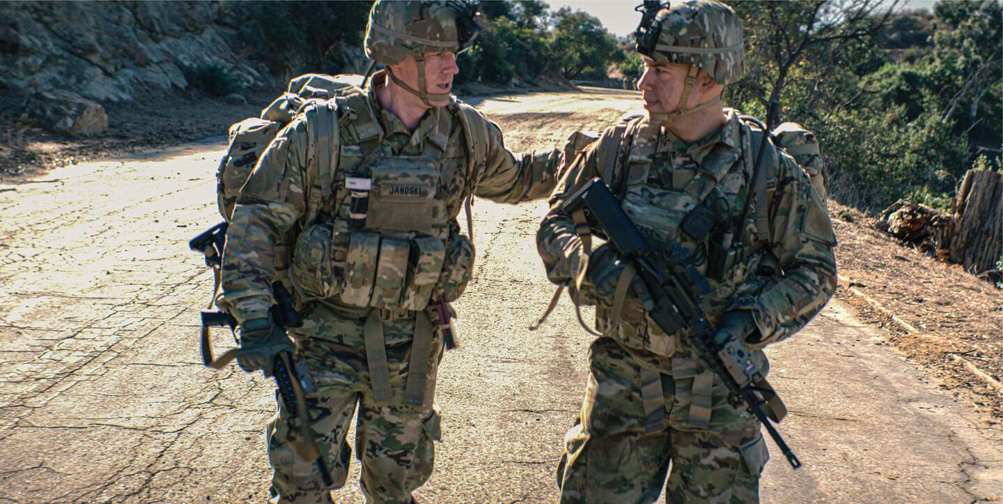 two soldiers in full gear talking while walking
