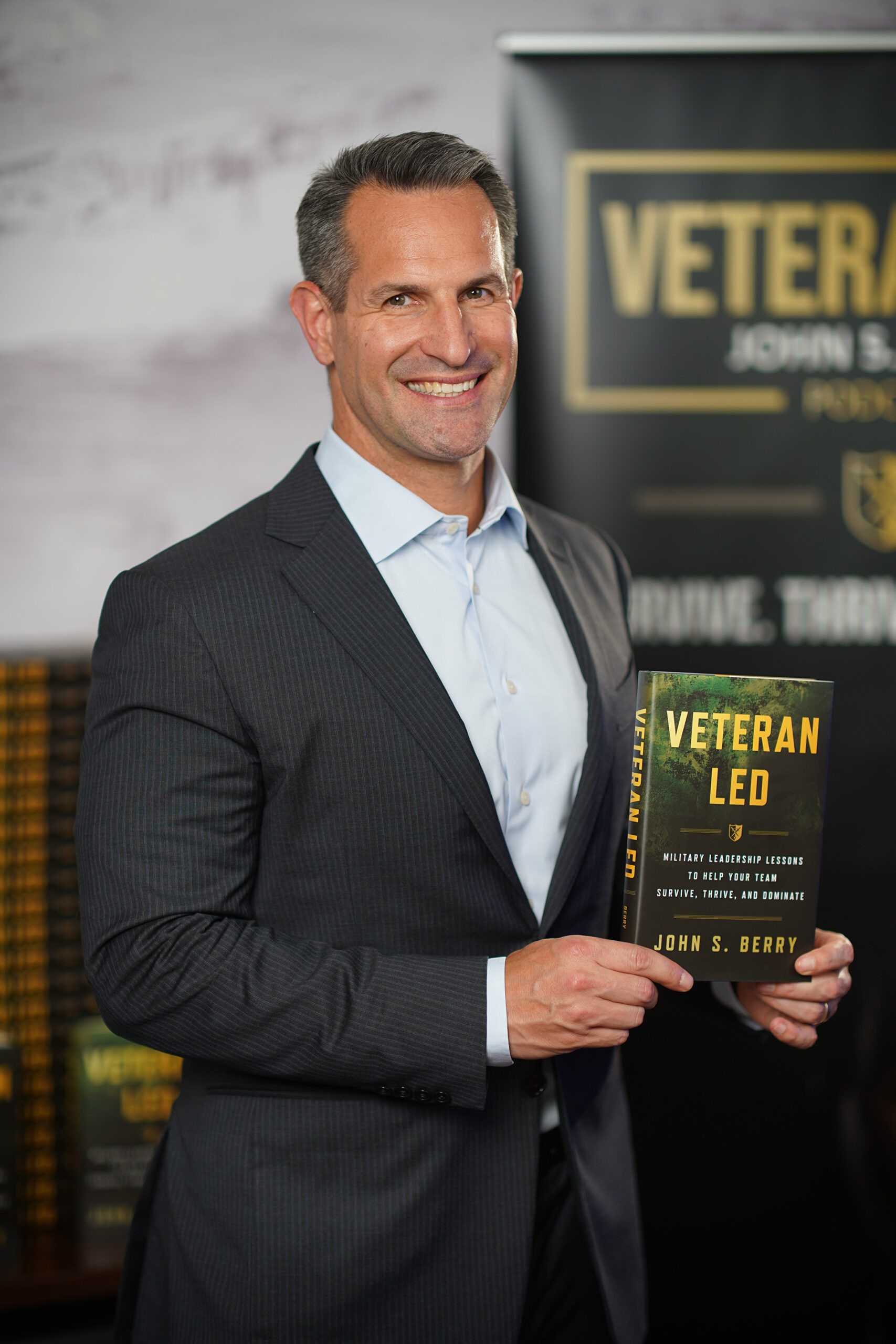 John S. Berry holding his book Veteran Led against a Veteran Led backdrop for his book launch